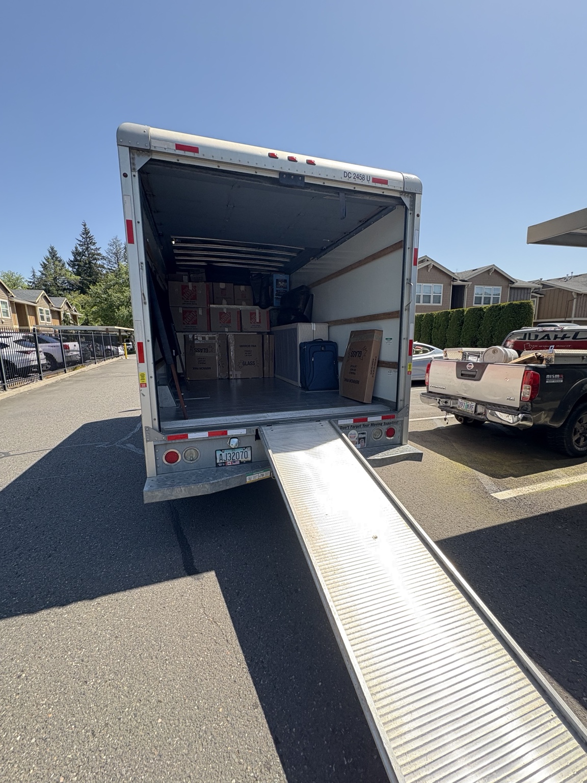 An open rental truck with a loading ramp in an apartment parking area.